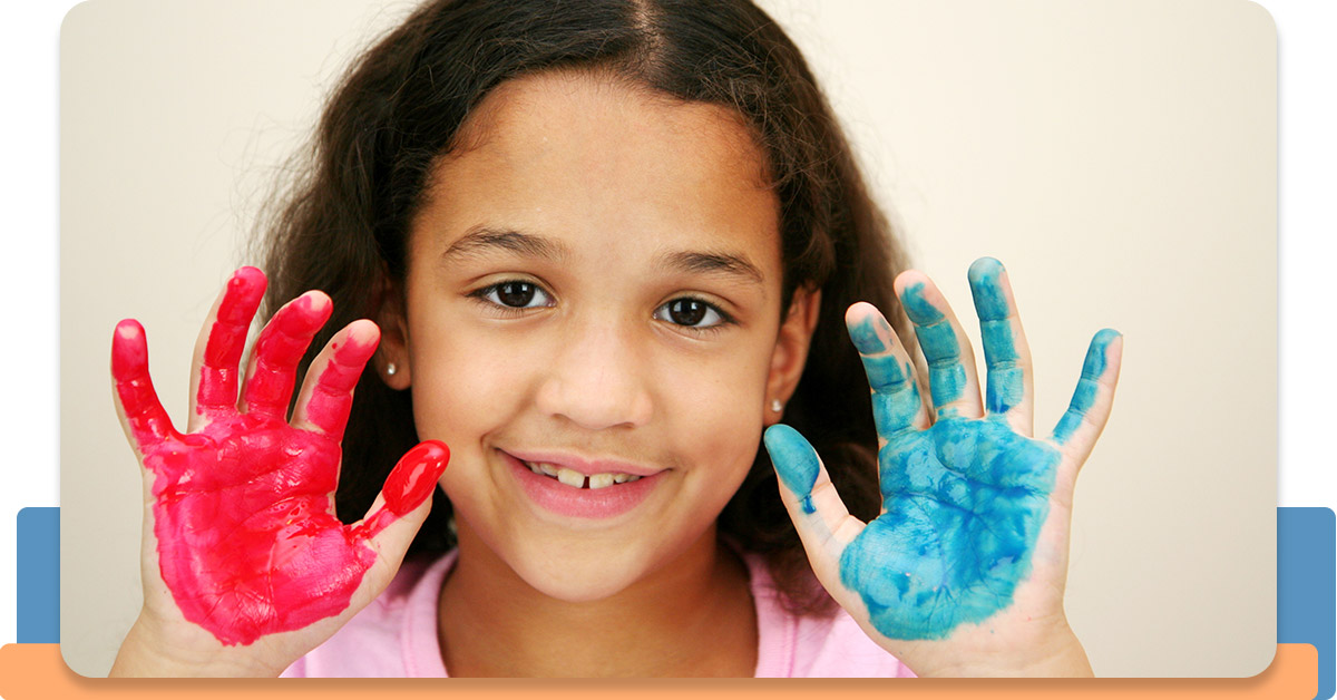 Female student smiling with paint on her hands.