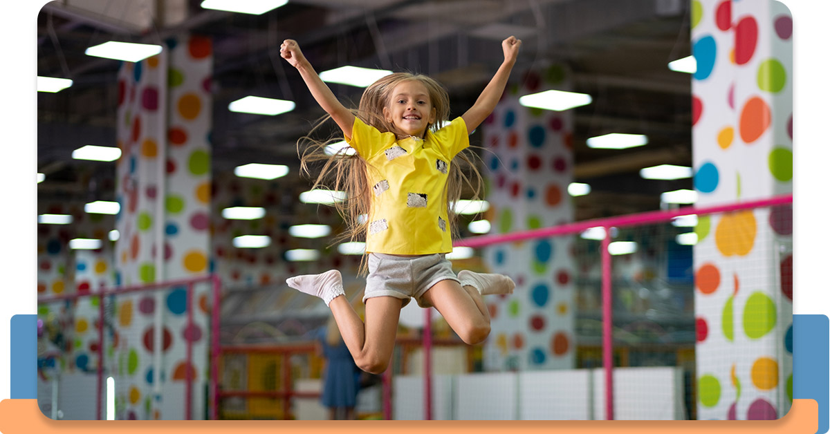 oung girl with pigtails jumping on an indoor trampoline.
