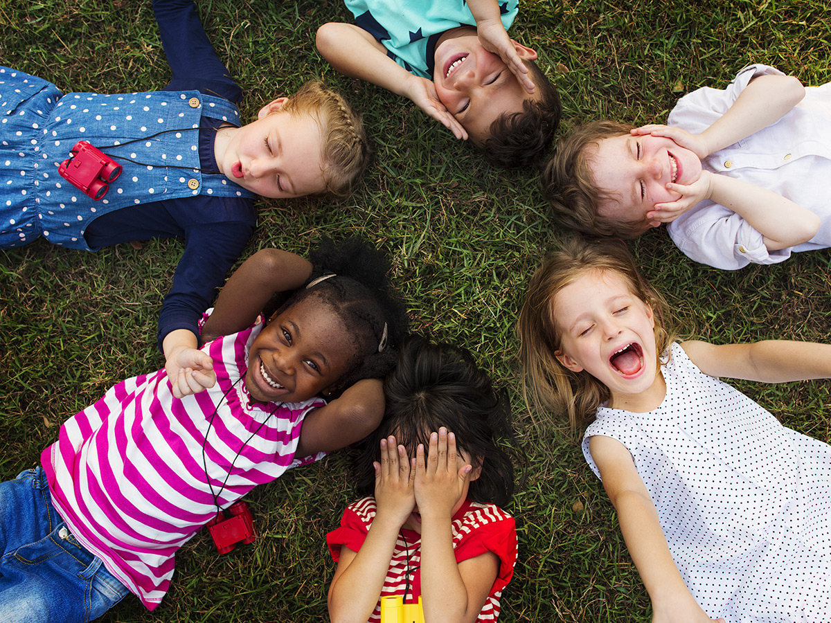 A group of diverse children lying in the grass