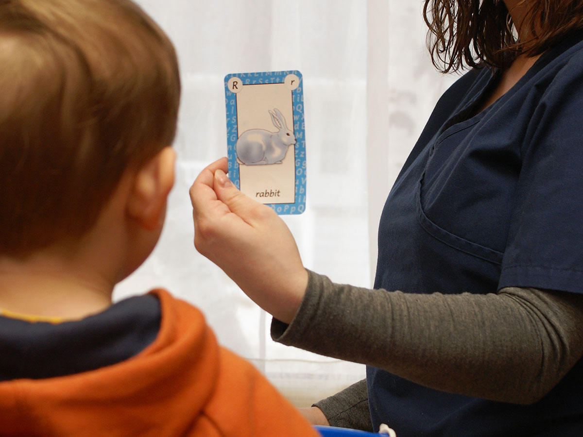 Teacher showing boy a picture card
