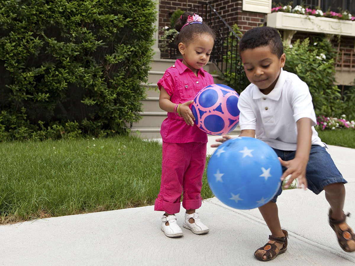 Two kids playing outside with bouncy balls