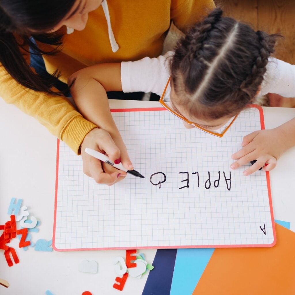 A young autistic girl writing letters.