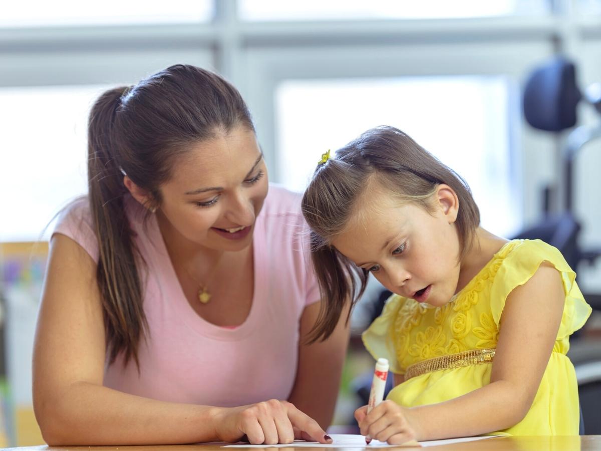 Child drawing with teacher