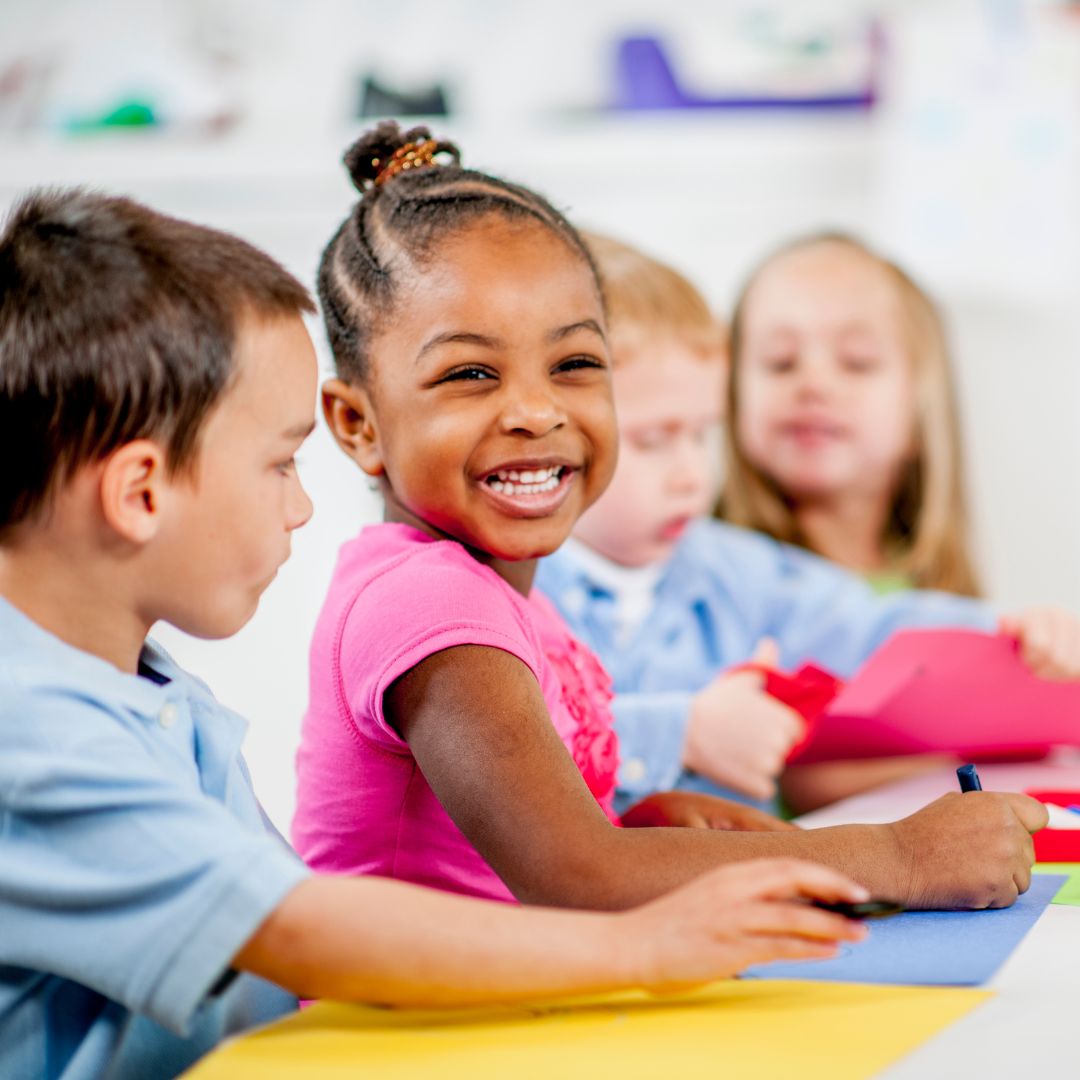 Child smiling while sitting at table with other children