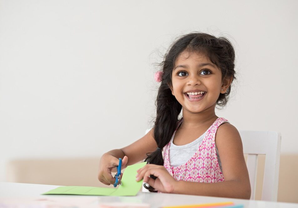 a young girl cutting a piece of paper